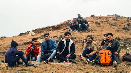 A group of people sitting on the hilltop.