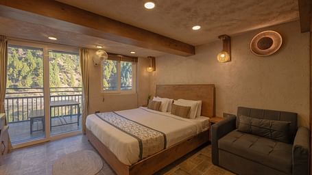 Room with double bed, balcony doors, wooden beams on the ceiling, and soft lighting.