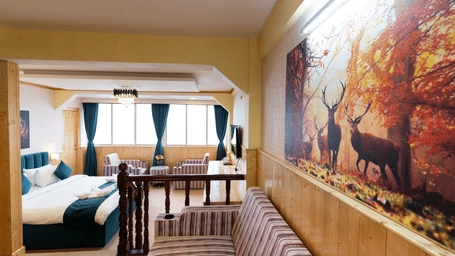 Suite with a king size bed, wall-mounted television, wooden table, and cosy lighting along with attached living room at Avianna Seven Seas, Darjeeling