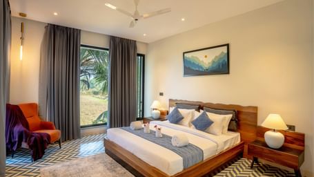 A cosy room featuring a neatly made bed, matching side tables, a large window that fills the space with natural light, and contemporary furnishings