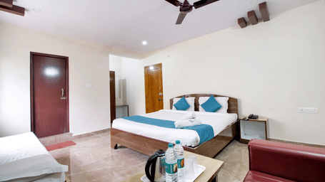 A clean, contemporary guest room with a double bed, white walls, and a small wooden desk under a wall-mounted television at beestay Hotels, MVP Colony, Vizag.