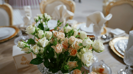 Close-up of a white and peach rose floral centre piece arranged on an elegant event table.