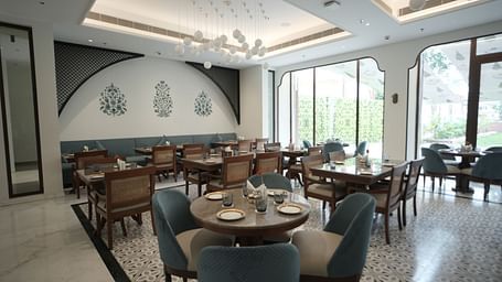 A brightly lit dining area with ample of natural lighting coming from the huge windows in the corner at Bhagirathi by RDB Atishay.
