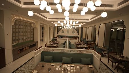 Full view shot of a restaurant with ample of warm lighting featuring well arranged dining tables along with cutlery Bhagirathi by RDB Atishay.