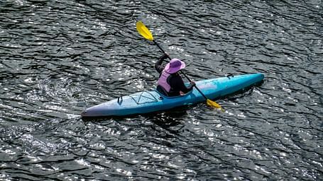 A solitary person kayaking in a waterbody as seen from above
