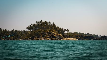 a view from the sea of palolem beach with trees and blue sky in the background