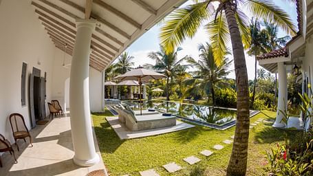 view of pool from a villa's verandah with a coconut tree in view - Caravela Beach Resort Goa