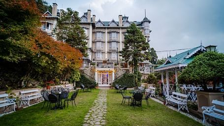 Stoned pathway in the lawn of Cedar Inn, Darjeeling leading to the hotel featuring a colonial architecture and multi-storey stature.