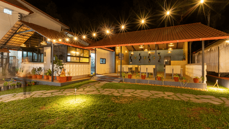 Nighttime view of a resort garden lawn illuminated by warm string lights and other outdoor lights.