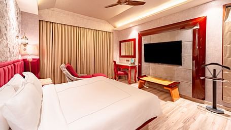 Executive Suite features a spacious bed, a wall-mounted television opposite it, and curtains covering the window at Crescent Spa & Resort, Indore