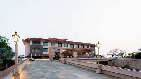 Facade view of Crescent Spa & Resort, Indore, set against a backdrop of a cloudy sky, showcasing its grand architecture