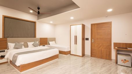 Wide view of the Daksh Pride room at Daksh Eden Greenz, Sasan Gir, showcasing its double, and single bed, wardrobe, and spacious layout.