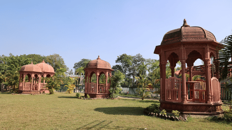 Decorative carved stone gazebos situated on a wide green lawn - DAN Resorts & Weddings, Palghar