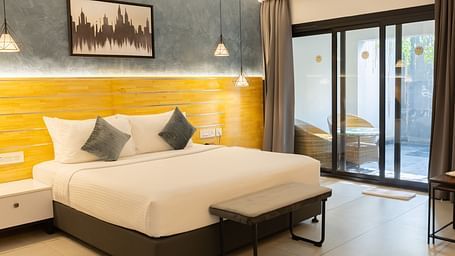 image of the garden view room featuring a plush king size bed with huge french windows in the corner - Darza Resorts
