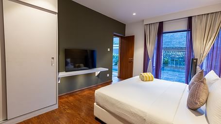 image featuring a plush double bed placed in front of a wall mounted television at the luxury villa - Darza Resorts