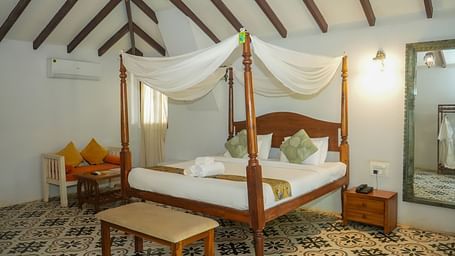 A room with a four-poster bed and seating area at at De Soul Santé, Morjim.