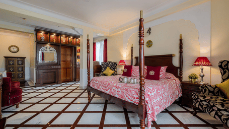  Guest bedroom with pink bedding, lampshade, and black-and-white tiled flooring at Dera Rawatsar, Jaipur.