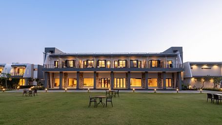 Facade view of DLS Forest Vines Resort, illuminated by warm lights from the windows and doors.