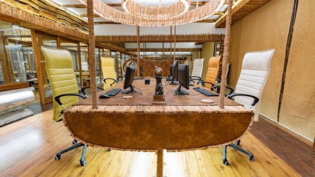 An Earthitects office interior featuring a long wooden desk, modern chairs, and heavy timber structural beams.