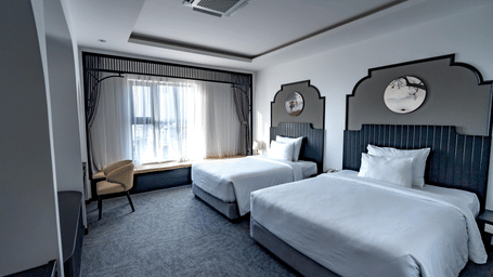 A modern bedroom contains 2 separate beds, grey carpeting, and large windows providing plenty of natural light.