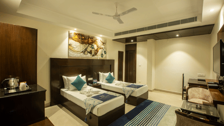 A modern superior room featuring two twin beds with blue and white striped runners and contemporary wall art — Eastlynn Resort, Rishikesh