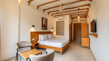 Room with a king size bed, chair, table, and television opposite at Ekawa Ganga, Rishikesh.