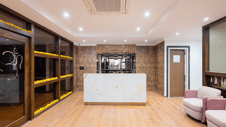 A clean, modern hotel bathroom featuring a large walk-in shower with a glass screen, a white basin, and large-format grey tiles at ELYSIUM Premier Suites, HITEC City.