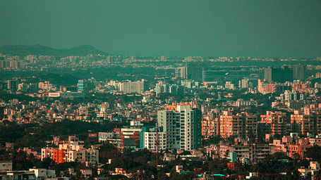 An overview of the city of Pune with high rise and small buildings in view in daylight.