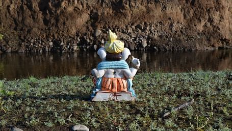 An overview of the hindu deity Ganesh's Idol in front of a waterbody.