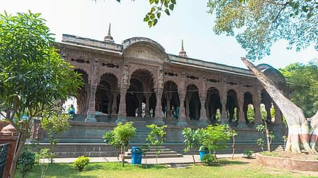 An overview of Rajwada palace in Indore with a garden and trees in front of it.