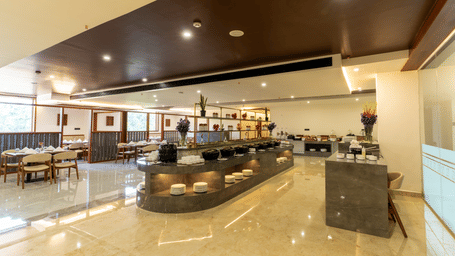 hotel dining area with a central buffet counter and seating area at Essentia Resort & Spa, Sirsi 