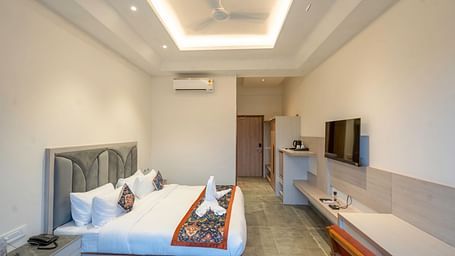 A bright and airy hotel room with a king size bed, a flat-screen TV, and a kitchenette.