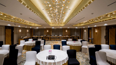 Galaxy 1 banquet hall at Gemini Continental featuring a decorated ceiling, a carpeted floor, and multiple round tables with chairs.