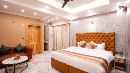 A spacious bedroom with an orange tufted headboard, marble floors, and a private seating nook - Golden Oak By The Lake Hill, Khurpatal