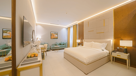 The ADA-friendly Deluxe King Room at Grand Iva Hotel, Abha, seen with a plush king size bed, bedside tables, bright lighting, an upholstered seating area by the wall, panelled walls, and curated interiors | Grand Iva Hotel, Abha