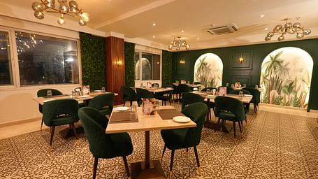 Contemporary dining area with elegant chairs and wall art at Grand Plaza Lords Inn Jammu.