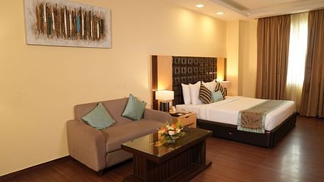 Spacious hotel room with a bed, seating area, and large window - Grand Plaza Lords Inn Jammu