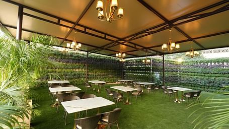 Outdoor seating area with grass flooring and canopy roof at Grand Plaza Lords Inn Jammu.