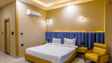 Wide-angle view of a contemporary bedroom with neutral walls, a king size bed, integrated ceiling lighting, and a wall-mounted air-conditioner – Grassfield Riviera Resort
