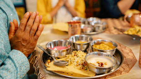 A traditional Indian wedding ritual setup with plates of offerings, flowers, and hands joined in prayer during the ceremony.