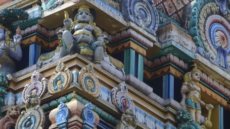 Close-up of intricate carvings and colorful sculptures on a gopuram showcasing vibrant Dravidian architecture and mythological figures.