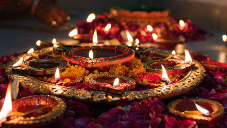 Decorative oil lamps (diyas) glowing amidst flowers, celebrating the festive spirit of Diwali