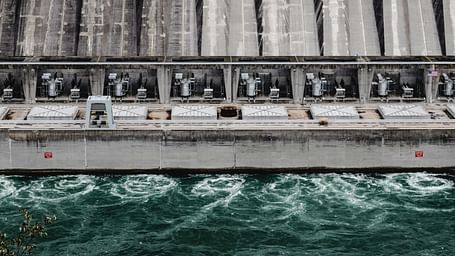 Massive dam with cascading water creating swirling currents below.