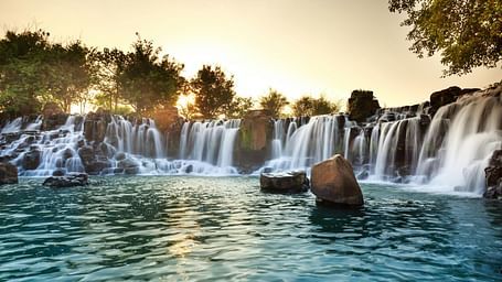 Majestic waterfall cascading over rocks surrounded by lush greenery.