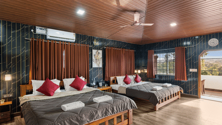 Double beds against dark accent wall in Quad Room With Forest View at Hatti Eden Coorg.