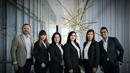 A diverse business team in formal attire posing in a modern office setting. 
