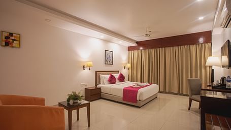 Comfortable hotel room at Diamond Palace Lords Plaza with a double bed, seating area, work desk, and a large window.