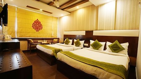 Family Room featuring two large king size beds with green accents, a wooden floor, and warm lighting. 