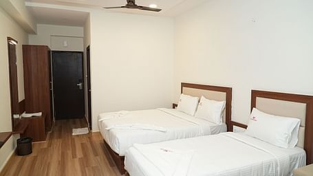 a room featuring a double bed along with a single bed with a wardrobe at the far end of the room - Hotel Grand Sigma