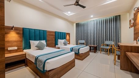 King Twin Bed Room with two single beds, teal headboards, and seating area at Hotel Highway King, Bilaspur.